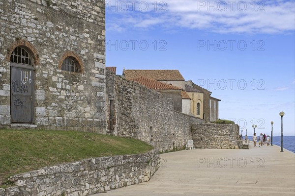 Tourists walking on promenade along ancient city wall in the town Pore?, Parenzo, seaside resort at