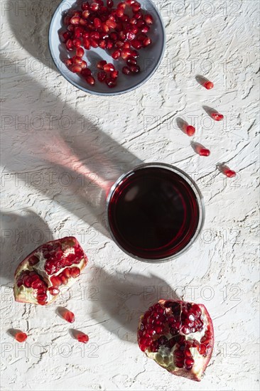 Glass of pomegranate juice on a white concrete background. Hard light, contrast. Top view, close