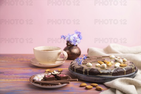 Homemade chocolate brownie cake with caramel cream and almonds with cup of coffee on a colored and