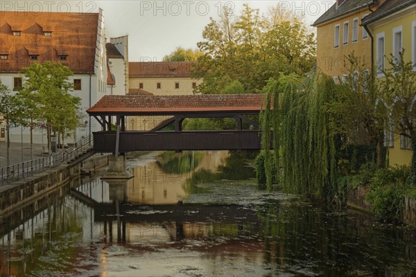The old ship bridge leads over the calm river Vils with reflection in the water, Amberg, Upper
