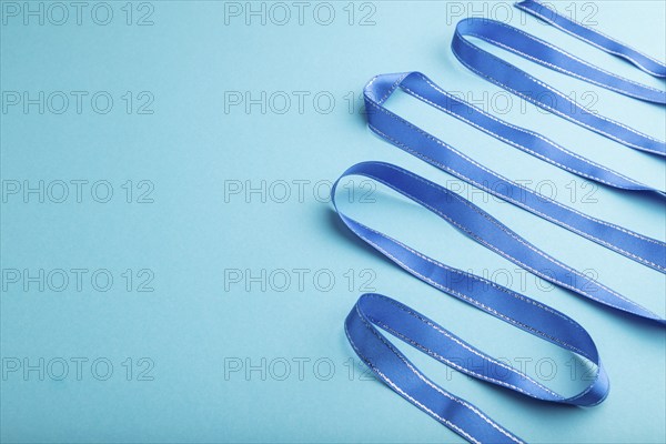 Blue ribbon on a blue pastel background. Celebration concept. Side view, copy space