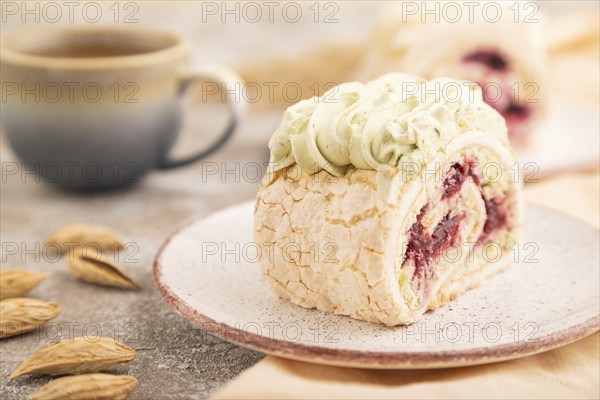 Roll biscuit cake with cream cheese and jam, cup of coffee on brown concrete background and orange