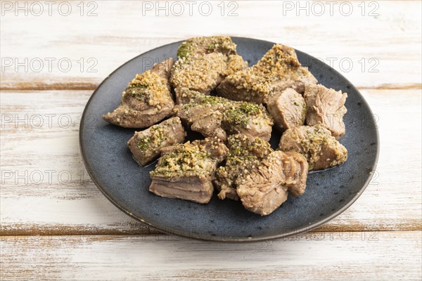 Stewed turkey fillet with garlic on white wooden background. Side view, close up