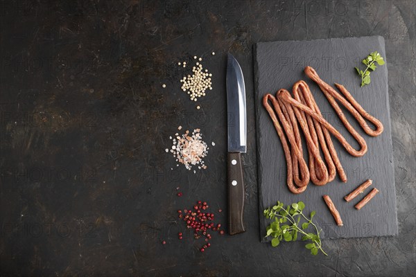 Traditional polish smoked pork sausage kabanos on a slate cutting board with salt and pepper on