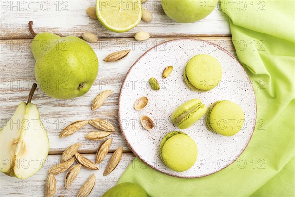 Green macarons or macaroons cakes with cup of coffee on a white wooden background and green linen