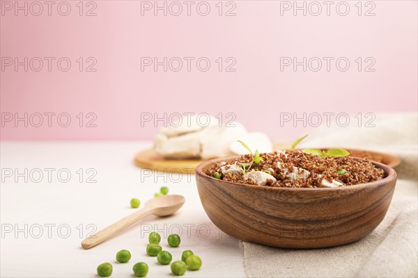 Quinoa porridge with green pea and chicken in wooden bowl on a white and pink background and linen