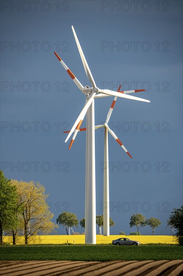 Wind turbines on a rape field, dark rain clouds, in the Rhenish lignite mining area, near