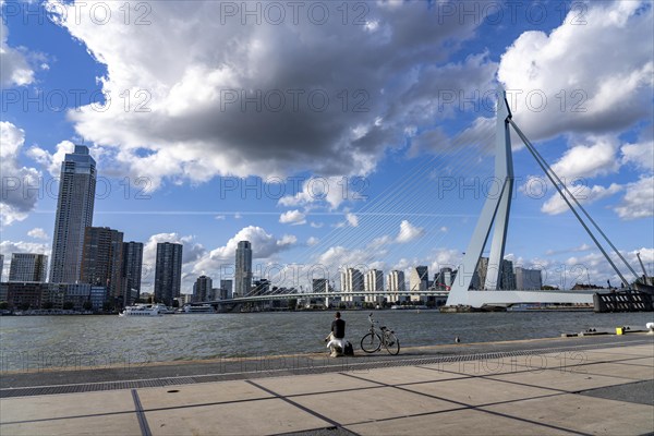 Skyline at the Nieuwe Maas, Erasmus Bridge, skyscrapers, man taking a break at the riverbank,