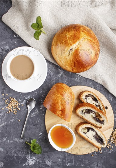Homemade yeast buns and rolls with poppy seeds and honey on a black concrete background with a cup