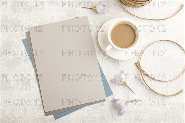 Gray paper sheet mockup with spring snowdrop crocus flowers and cup of coffee on gray concrete