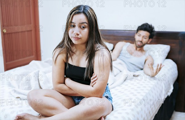 Wife arguing with her husband in bed. Young couple arguing sitting on the bed. Upset woman with