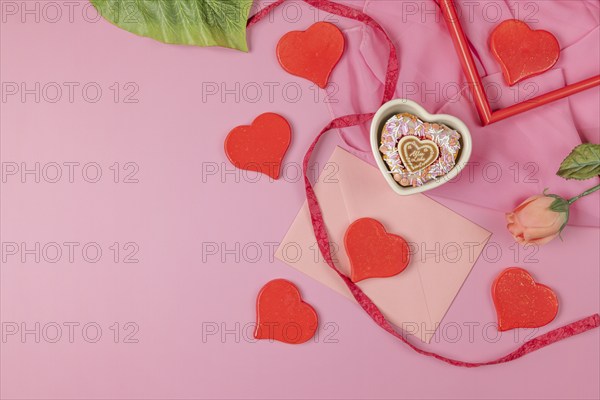 Bright red hearts scattered around a pink envelope and a single rose, Valentine's Day, heart-shaped