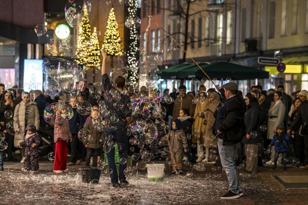 Pre-Christmas season, street artists, creating large soap bubbles, at Schadow-arcades, in the city