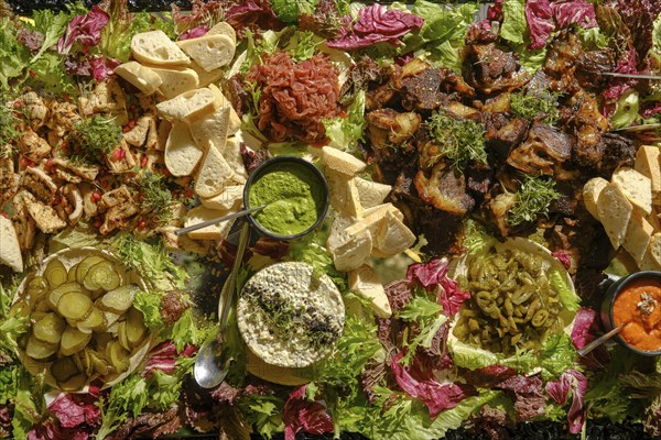 An elaborate arrangement of Mediterranean dishes showcases grilled meats, fresh vegetables,