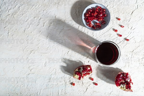 Glass of pomegranate juice on a white concrete background. Hard light, contrast. Top view, copy