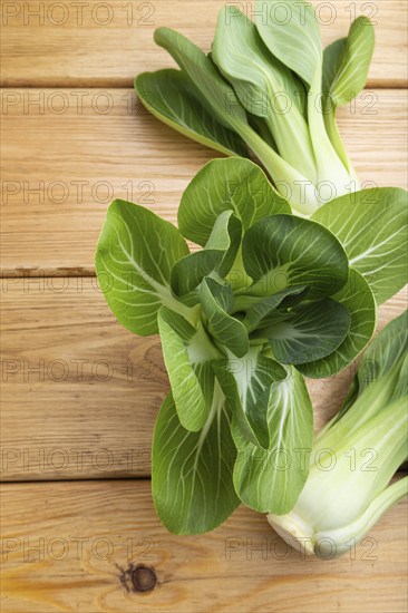 Fresh green bok choy or pac choi chinese cabbage on a brown wooden background. Top view, close up,