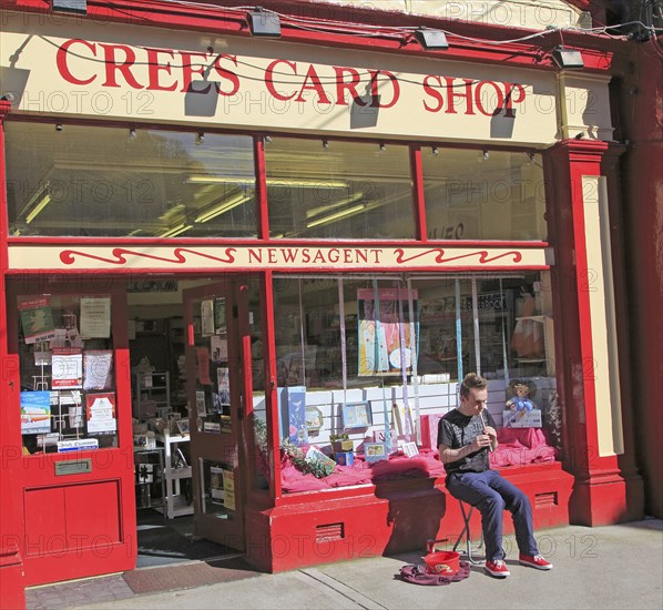 Boy busking playing tin whistle outside shop, Youghal, County Cork, Ireland, Irish Republic, Europe