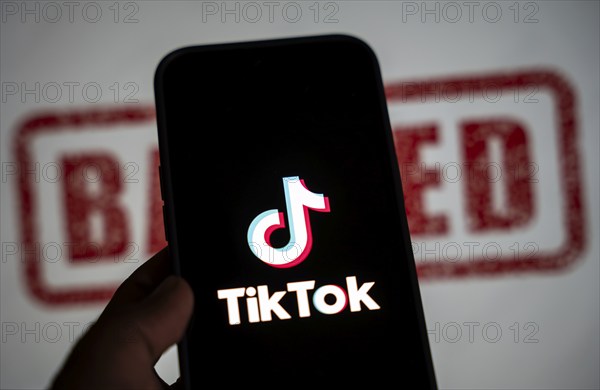 In this photo illustration, logo of Tiktok is displayed on mobile phone screen next to ban sign, in