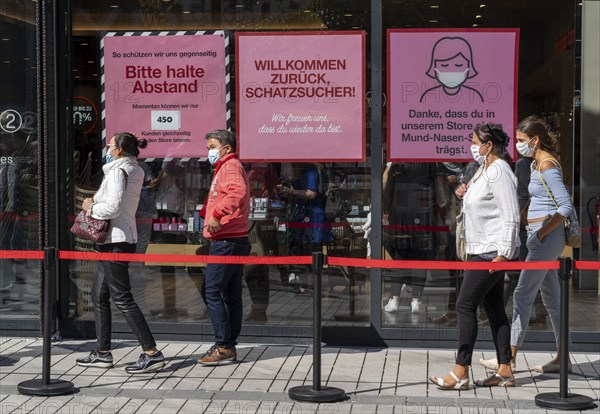 Queue in front of a clothing shop, Corona protective measures, posters for compulsory masks,