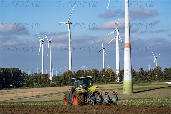 Farmer working in the fields, with a tractor, wind farm above the village of Lichtenau,