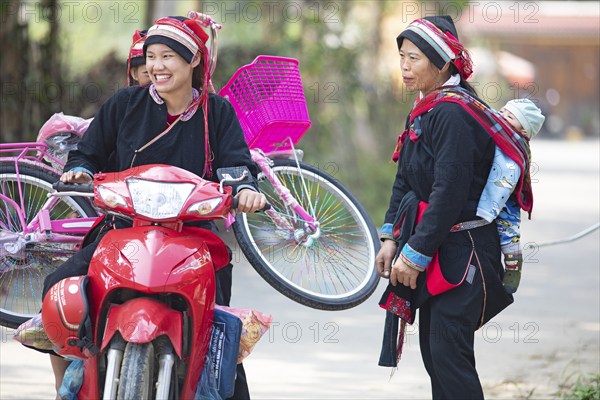 Vietnamese woman in traditional traditional costume from the Dao minority transport a pink bicycle