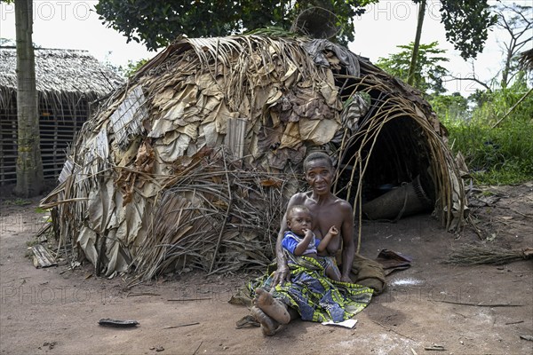 Pygmy woman of the Baka or BaAka people with her child in front of her hut, Bayanga, Sangha-Mbaéré