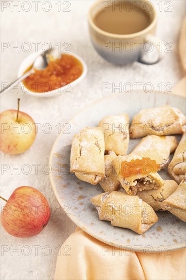 Homemade sweet cookie with apple jam and cup of coffee on gray concrete background and orange linen