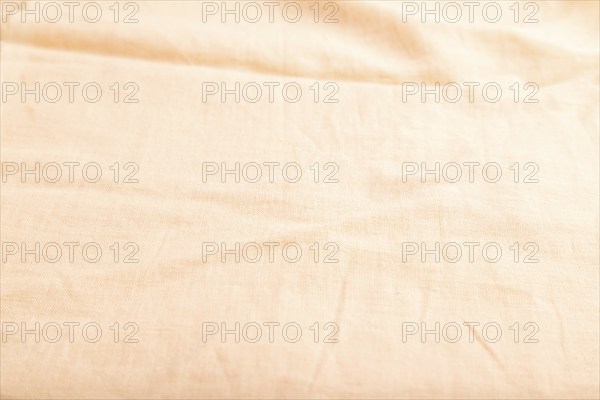 Fragment of smooth orange linen tissue. Side view, natural textile background and texture