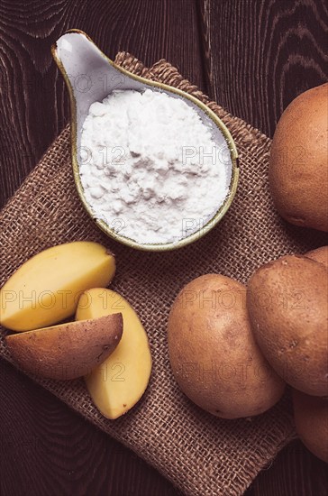 Potato starch, on a wooden table, close-up, rustic style, no people, potatoes, ceramic spoon,