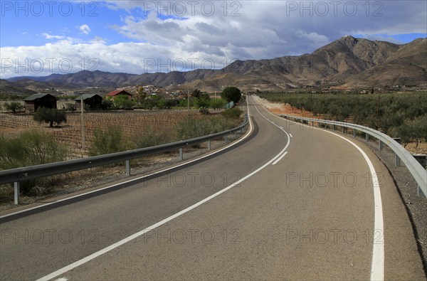 Modern road leading to mountains of Sierra de Baza range near village of Uleila del Campo, Almeria,