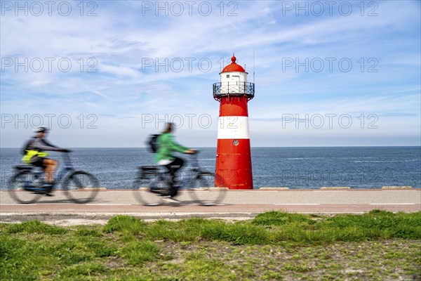 North Sea dyke near Westkapelle, Westkapelle Laag lighthouse, cyclists on the Zeeuwse Wind Route