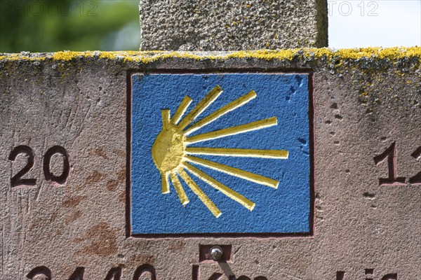 Stone slab with blue shell, showing pilgrims on the Way of St James the way to Santiago de