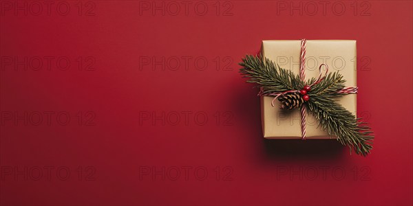 Banner with small Christmas gift box wrapped in graft paper on red background with copy space.