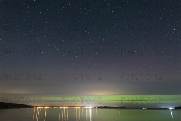 Northern lights (aurora borealis) shine on a starry night over Lake Plau, Ganzlin,