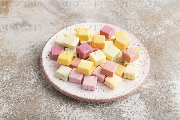 Various fruit jelly chewing candies on plate on brown concrete background. apple, banana,