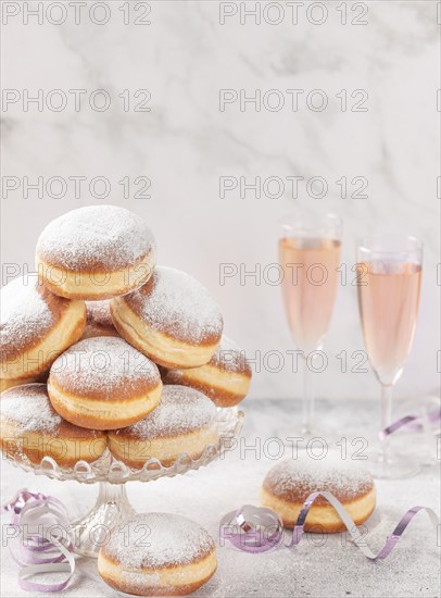 Doughnuts on a glass stand with rosé sparkling wine in the background, copy room