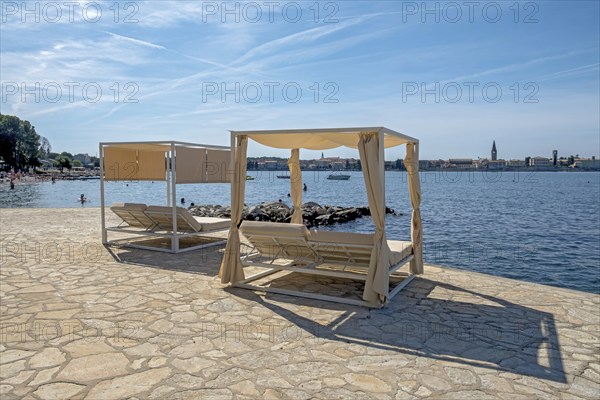Sun loungers under a canopy by the sea, with a view of Porec, Istria, Croatia, Europe