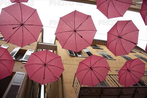 In the perfume town of Grasse, red umbrellas hang between the houses, Grasse, Provence-Alpes-Côte