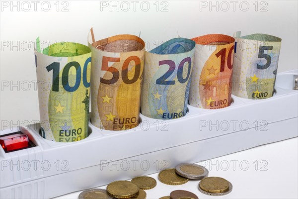 Symbolic image of electricity costs: Multiple socket outlet with banknotes