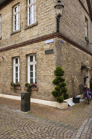 Historic brick house with lantern and mock cypress (Chamaecyparis) at Schweinemarkt in Warendorf,