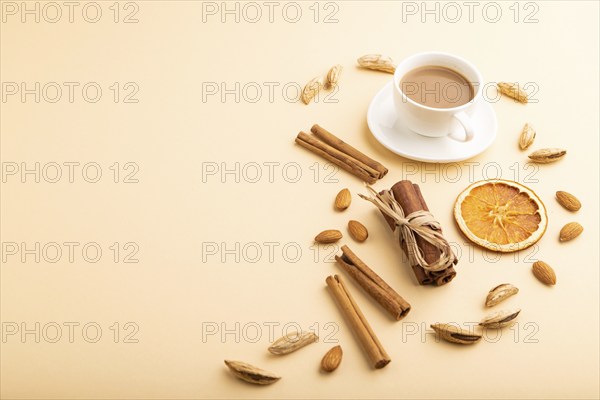 Composition with almonds, cinnamon and cup of coffee on orange pastel background. Blank, side view,