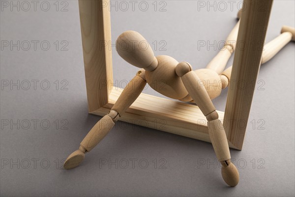 Wooden mannequin crawl out of a wooden frame on gray pastel background. escape, break rules,