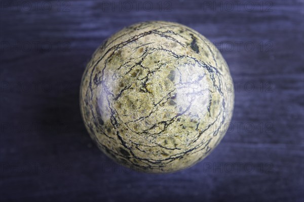 Green serpentine sphere on a black background, close up