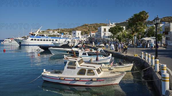 Lively harbour with many boats and white buildings surrounded by blue sea and sky, Skala, Patmos,
