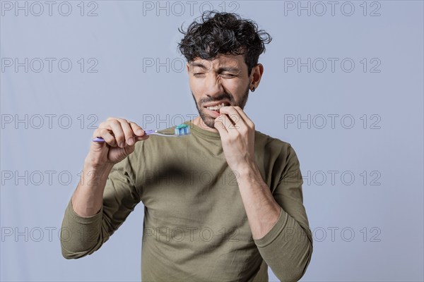 Young man holding toothbrush with gum pain. Man holding toothbrush with gum pain, People holding