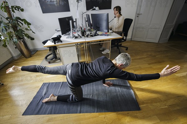 Symbolic photo on the subject of occupational health management. A woman exercises on a sports mat
