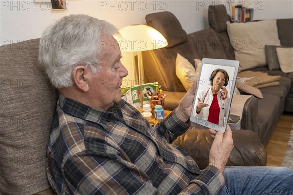 Symbolic image of telemedicine, elderly patient speaking to a doctor in a video conference from