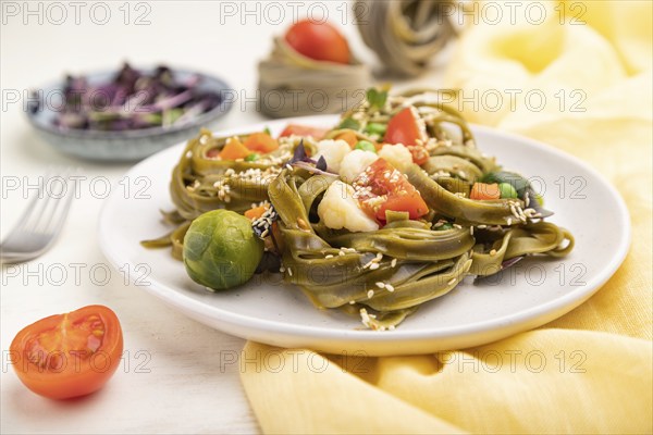 Tagliatelle green spinach pasta with tomato, pea and microgreen sprouts on a white wooden