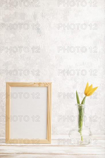 Wooden frame with orange tulip flower in glass on gray concrete background. side view, copy space,