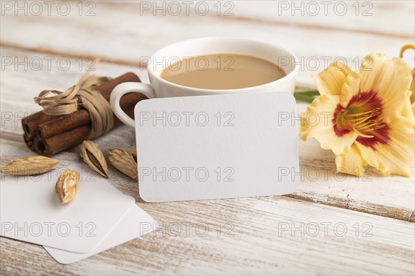 White paper business card mockup with orange day-lily flower and cup of coffee on white wooden